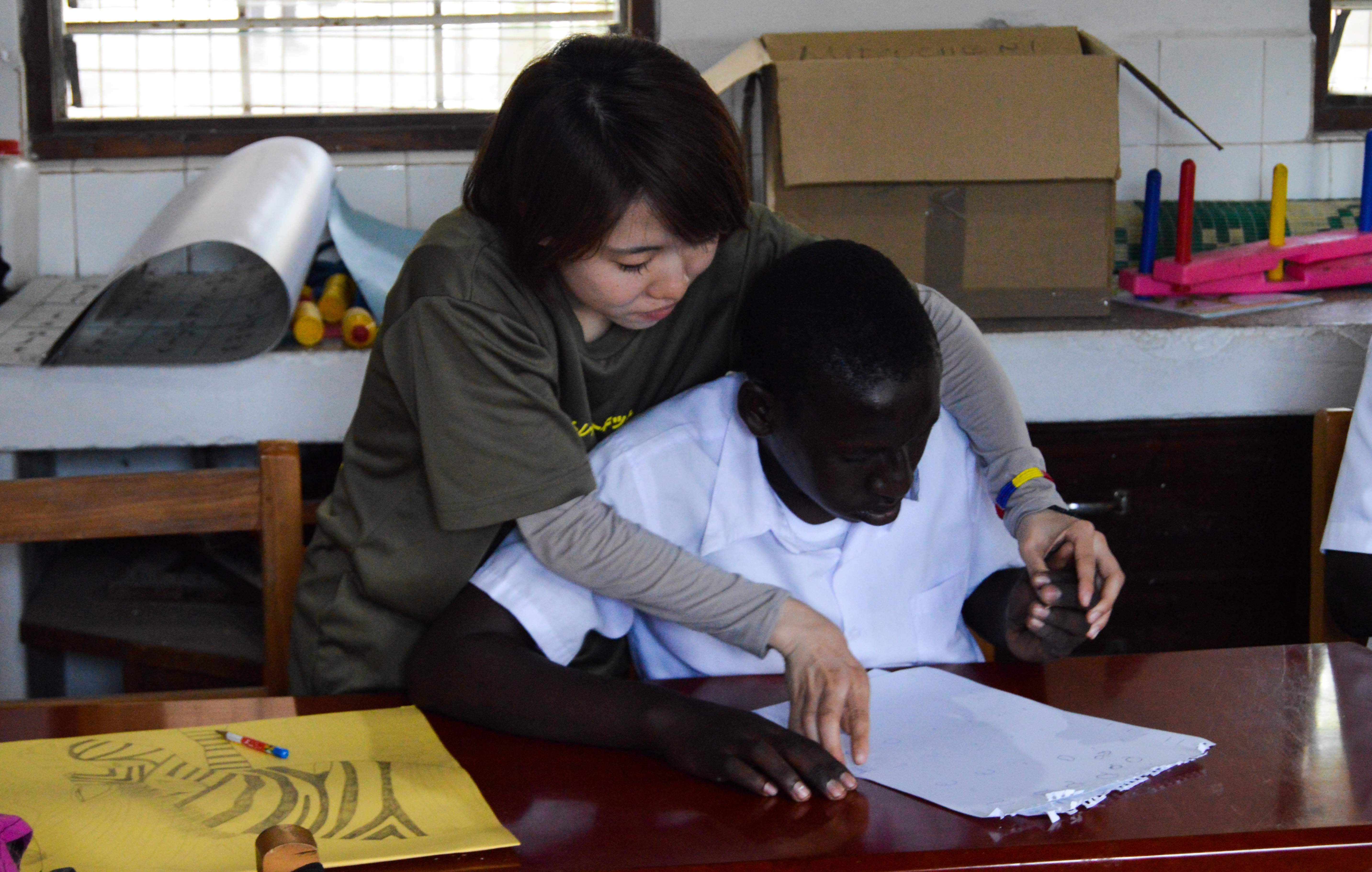 An experienced medical intern is seen helping a young handicapped boy learn how to draw and increase movement in his arms whilst on her medical occupational therapy internship in Tanzania with Projects Abroad. Projects Abroad experienced intern is pictured helping a boy learn to draw whilst on her medical occupational therapy internship in Tanzania.
